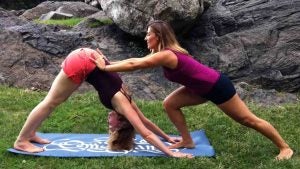women doing yoga with yoga mat and rocks at the back